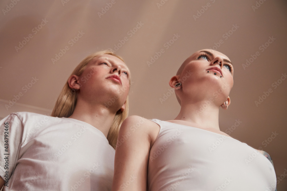 Womanly albino man with long blonde hair posing nearby bald masculine female Womanly albino man with long blonde hair posing nearby bald masculine female