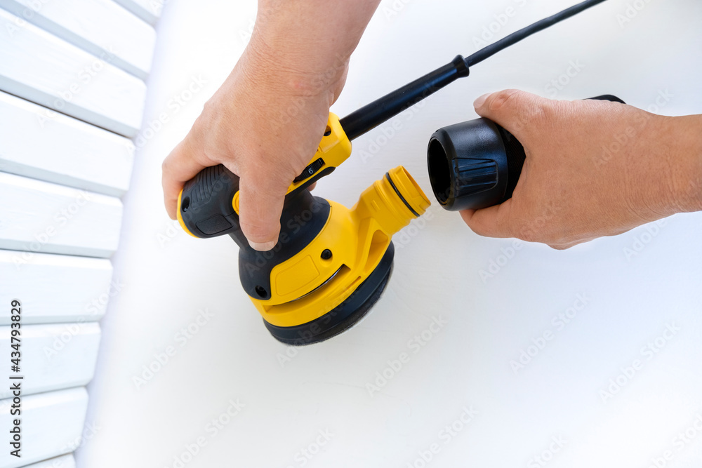Circular electric power sander, grinder tool,surface sanding machine with disconnected container for collecting dust and chips,in strong male hands on white background,horizontal banner,copy space Circular electric power sander, grinder tool,surface sanding machine with disconnected container for collecting dust and chips,in strong male hands on white background,horizontal banner,copy space