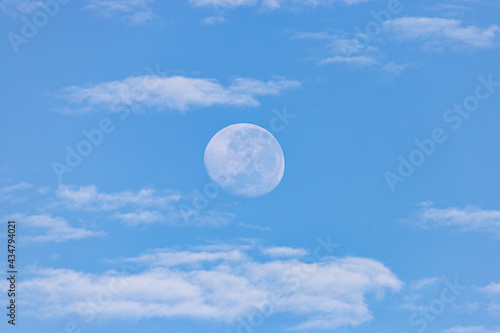 Moon in the day with clouds in the blue sky