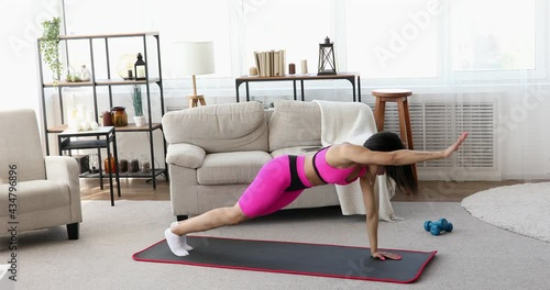 Sporty young black woman making lunges training at home. Athletic fit girl doing fitness aerobic exercises  in living room. Home fitness and wellness concept. photo