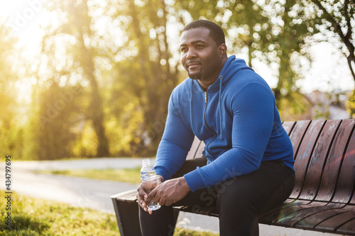 Man resting on bench after exercise and  drinking water . photo