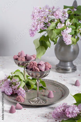 Belgian sweets cuberdon and pralines in silver glasses, spring still life with lilac flowers photo