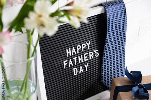 Happy Fathers Day concept. Letterboard with sign Happy Father's Day, gift box, flowers on table. photo