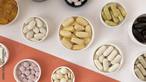 close-up of multivitamin biologically active supplements on white and coral background. mental wellbeing and  personal health concept