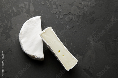 Camembert cheese halves on black stony table background