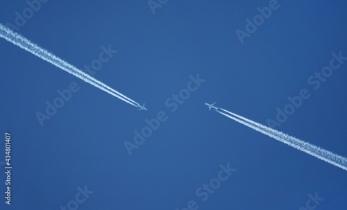 Two airplanes are approaching each other in the blue sky