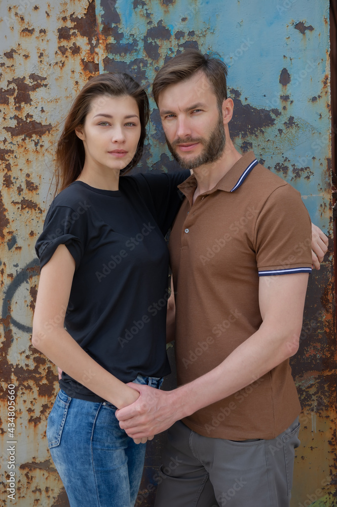 portrait of a pair of a beautiful woman with loose hair and a handsome man against the background of a metal painted wall.