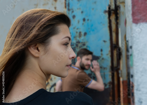 beautiful woman with loose hair looks to the side on a blurred background with a man.