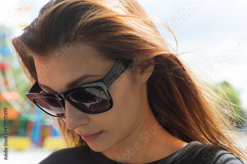 portrait of a pretty woman with flowing hair and sunglasses with her head down.