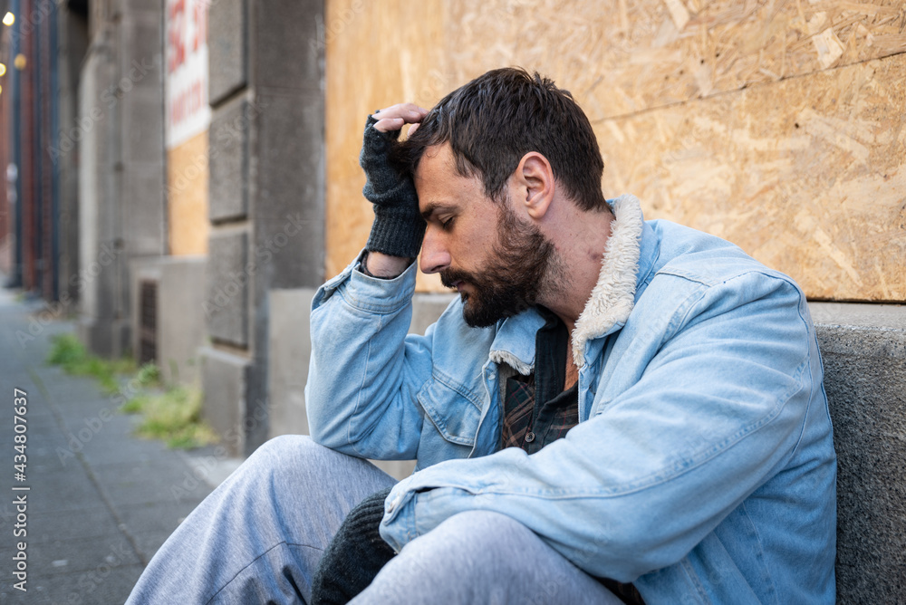Young hungry unemployed sick depressed homeless homeless man sitting on the street in the city begging for money waiting to earn something to buy food to eat, social documentary concept Young hungry unemployed sick depressed homeless homeless man sitting on the street in the city begging for money waiting to earn something to buy food to eat, social documentary concept