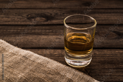 Glass of tequila with piece of cloth on an old wooden table. Close up view © Georgii Shipin