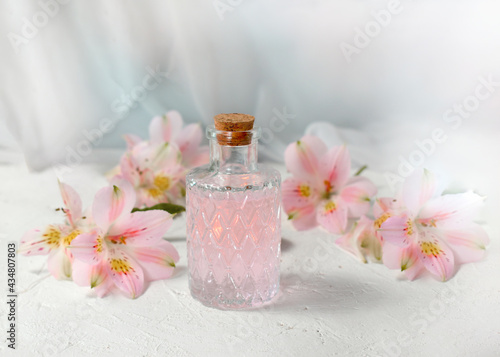 Aromatherapy or spa composition with cosmetics oil glass and flowers on light background. Romantic perfume greeting concept for Womans day, Mothers day or wedding. Copyspace