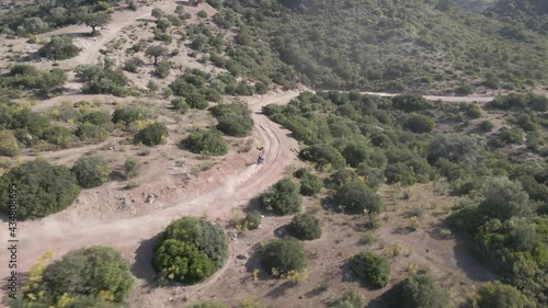 Aerial drone tracking shot of rider racing in a rally race speeding into the desert with dust and smoke trails.