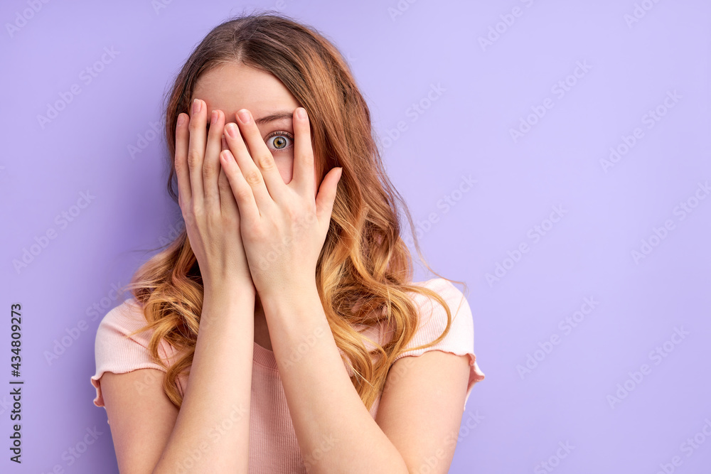 young pretty scared woman posing isolated over purple background covering face, frightened female stand in fear young pretty scared woman posing isolated over purple background covering face, frightened female stand in fear