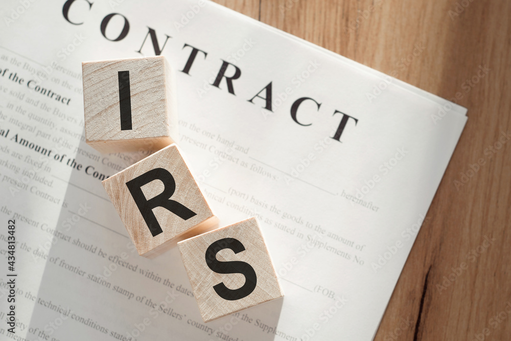 Word IRS on wooden cubes on contract documents background. Word IRS on wooden cubes on contract documents background.