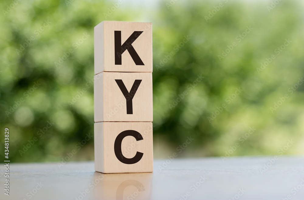 The word KYC - Know Your Customer, built from wooden cubes outdoors on the background of nature. The word KYC - Know Your Customer, built from wooden cubes outdoors on the background of nature.