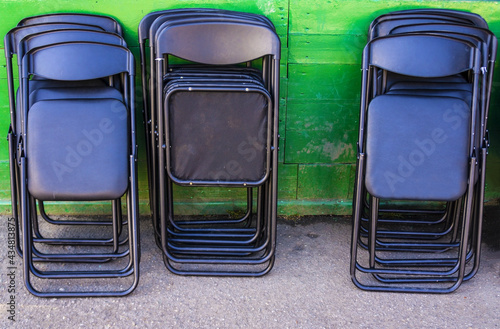 Black seats that fold. Folded  chairs on a green background