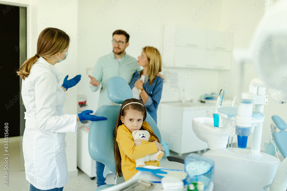 Child looking scared and hugging her toy while sitting in dental chair. Child looking scared and hugging her toy while sitting in dental chair.