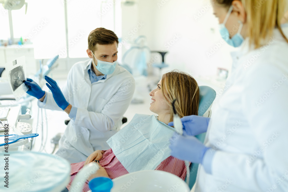 Photo of male dentist showing at patient's X-ray image in dental office. Photo of male dentist showing at patient's X-ray image in dental office.