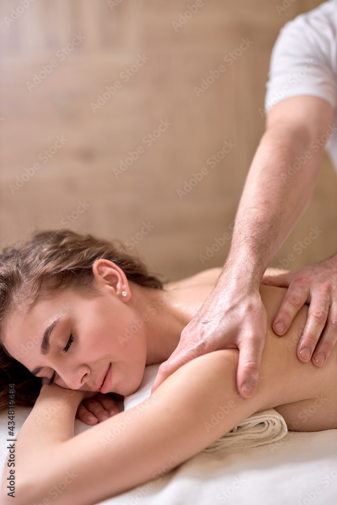 Problems of women body.Healthy massage for young woman in wellness center. Perfect skin. Unrecognizable Skilled Professional Masseur massaging back, shoulders, spine - obrazy, fototapety, plakaty 