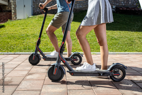 Two young people trying out a new electric kick scooter near their house