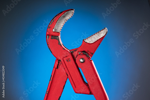 Red adjustable pipe wrench on a blue background