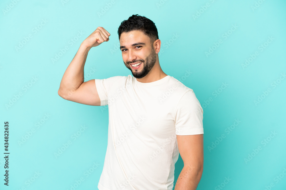 Young arab man isolated on blue background doing strong gesture Young arab man isolated on blue background doing strong gesture