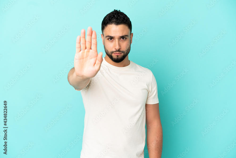 Young arab man isolated on blue background making stop gesture Young arab man isolated on blue background making stop gesture