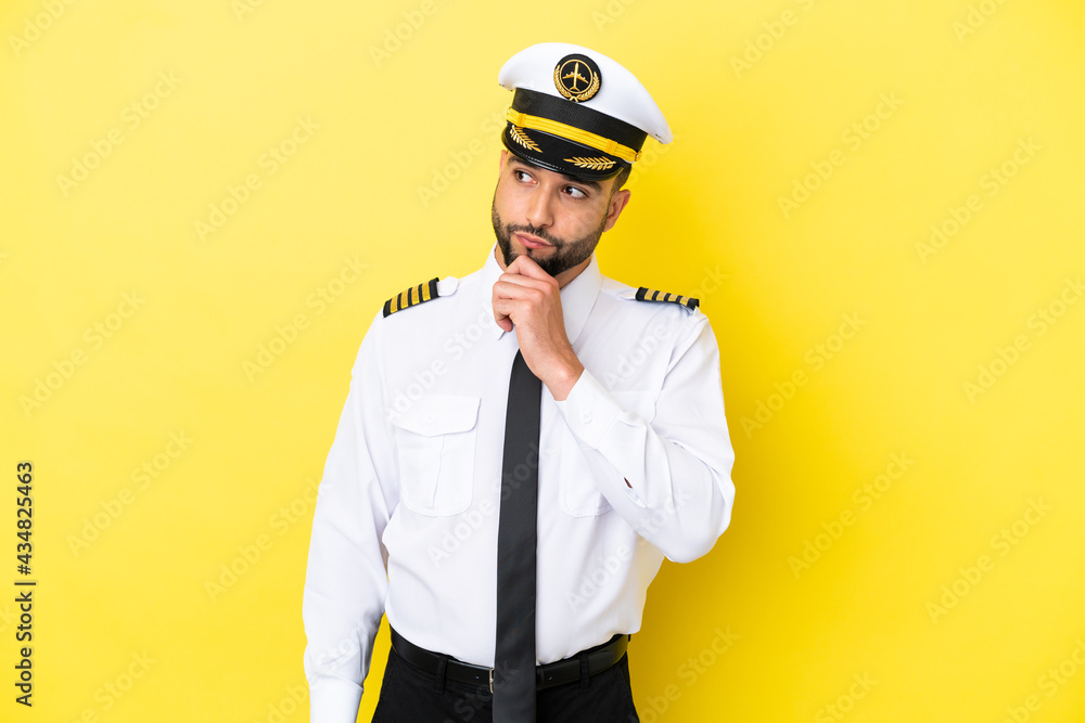 Fototapeta premium Airplane arab pilot man isolated on yellow background and looking up