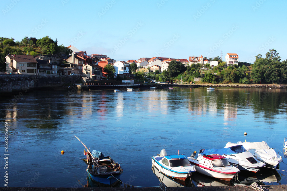 Pastoral landscape of a county town in Portugal. An embankment with small colorful houses and a river with boats.