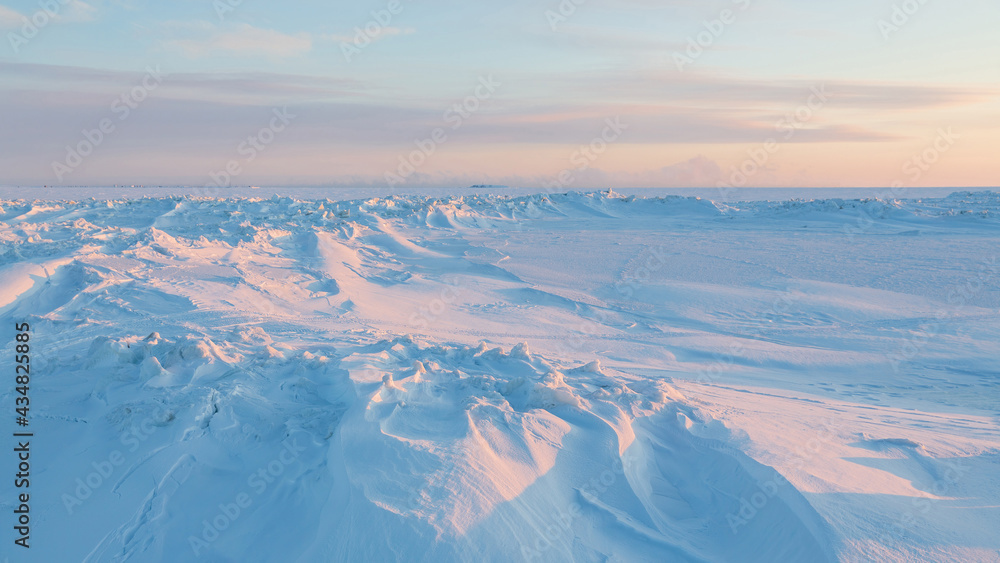 Winter arctic landscape. View of snow and ice at sunset. Ice hummocks on the frozen sea in the Arctic. Cold frosty winter weather. Harsh polar climate. Travel and hikes to the far north to the Arctic.