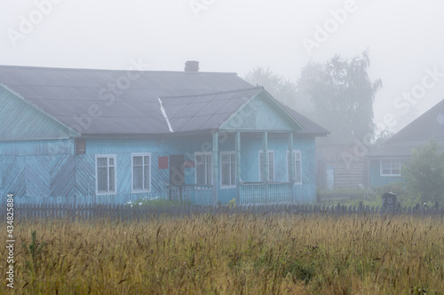 The old wooden building of the village administration and the police station. Morning fog in the countryside. Rural landscape. Demyanovsky Pogost village, Babushkinsky district, Vologda region, Russia