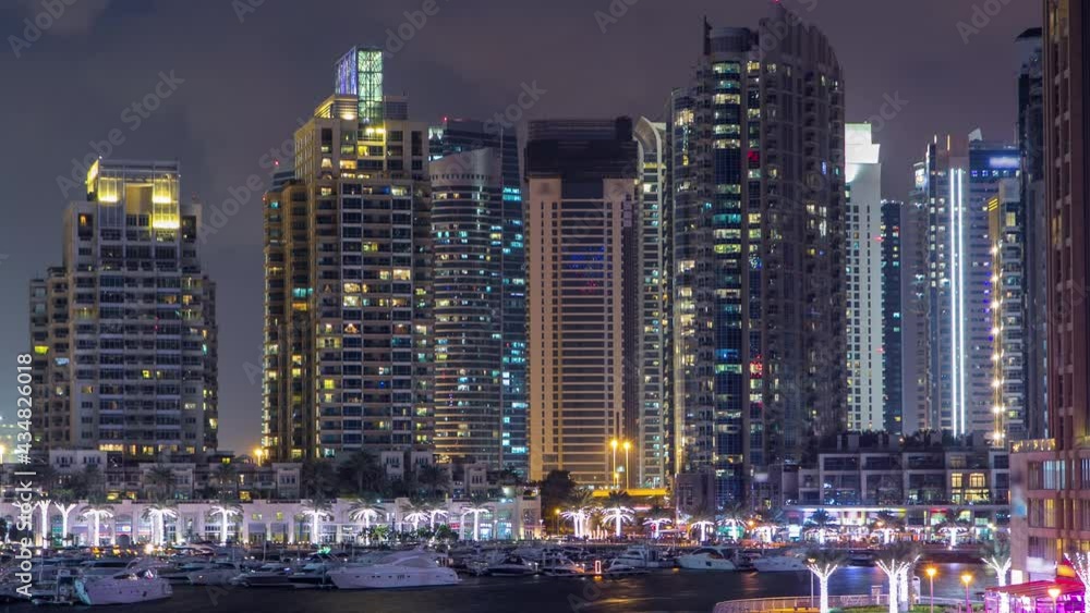 Dubai Marina waterfront with towers and yachts from bridge day to night transition timelapse, United Arab Emirates. Skyscrapers and boats after sunset Dubai Marina waterfront with towers and yachts from bridge day to night transition timelapse, United Arab Emirates. Skyscrapers and boats after sunset