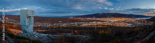 Evening panorama of the memorial complex Mask of Sorrow and the environs of the city of Magadan. View of the monument and the seaside town. Magadan, Magadan Region, Siberia, Russia.