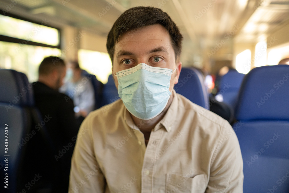 Travel safely covid 19 on public transport. Train passenger with protective mask travels sitting on seat with social distance in railway carriage , new norm. Travel during coronavirus pandemic