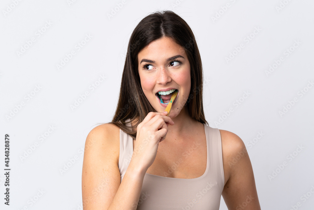 Teenager Brazilian girl brushing her teeth over isolated white background Teenager Brazilian girl brushing her teeth over isolated white background
