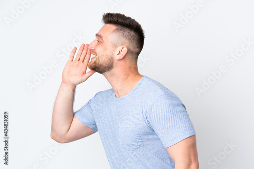Russian handsome man over isolated background shouting with mouth wide open to the side
