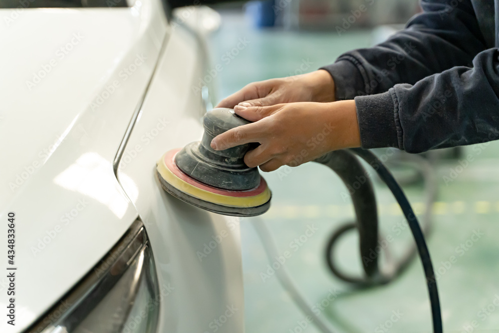 Spanish worker sands the entire car for a customer. Madrid