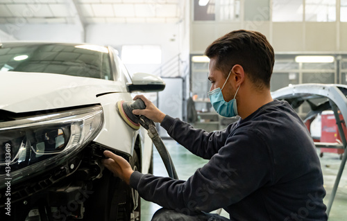 A poor Spaniard is hard at work sanding the side of his client's car, Madrid. photo