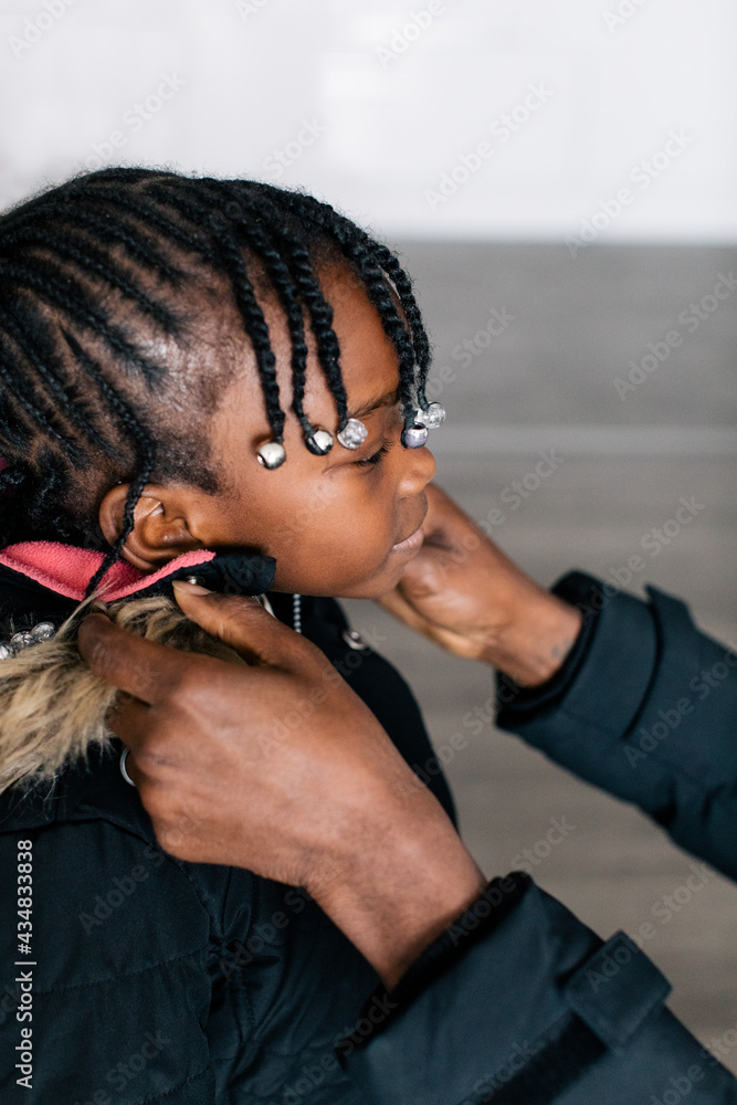 Father helps daughter with braids to put on her coat