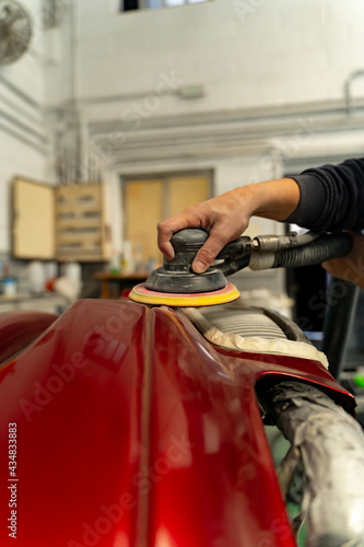 Man working in his workshop sanding a car bumper. Madrid.