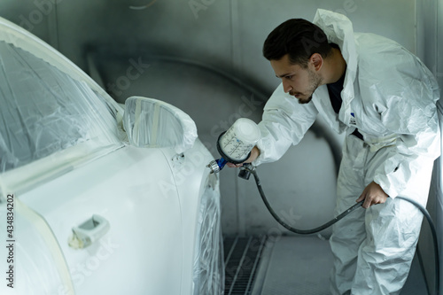 Specialist car painter examines and paints his customer's vehicle. Madrid