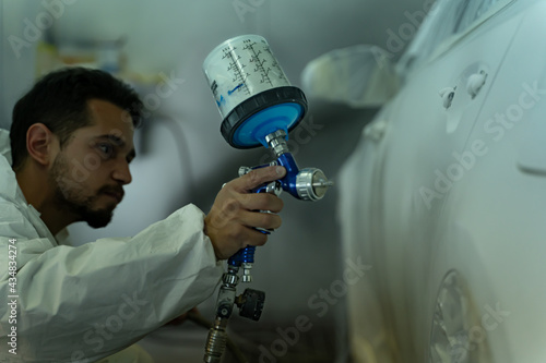 Canvas Print Young guy works very hard to have the car perfectly painted on time