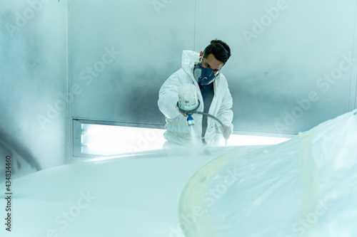Obraz na płótnie Hardworking Spanish guy paints pearl white car in the box, Madrid w salonie