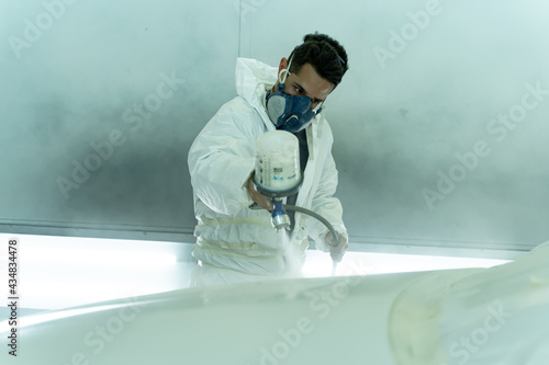 Obraz na płótnie Dark-haired man paints the hood of a car in his own store. Madrid w salonie