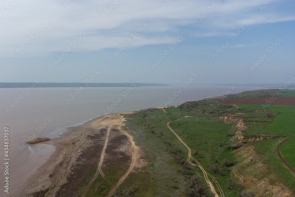 The coast of the Kuyalnitsky estuary in the spring. Sandy cliff, beach and pond. Aerial view.