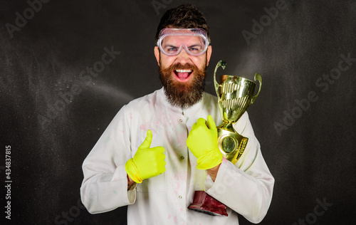 Professional cleaning service. Bearded man in uniform and gloves with gold trophy cup.