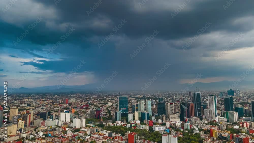 Drone hyperlapse top view flies over business, industrial and financial district of Mexico City, with skyscrapers and cityscape of Paseo de la Reforma, on a dramatic cloudy rainy day before the sunset