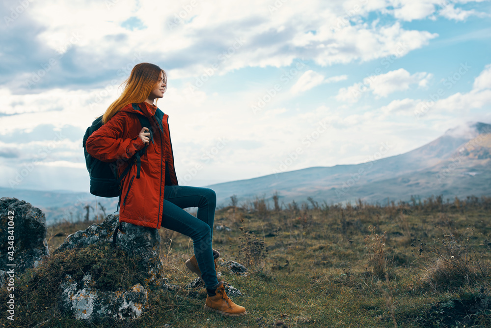 woman on nature in the mountains sits on a stone and autumn landscape