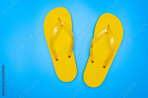 yellow rubber flip-flops isolated over blue background, pair of thongs, shot above